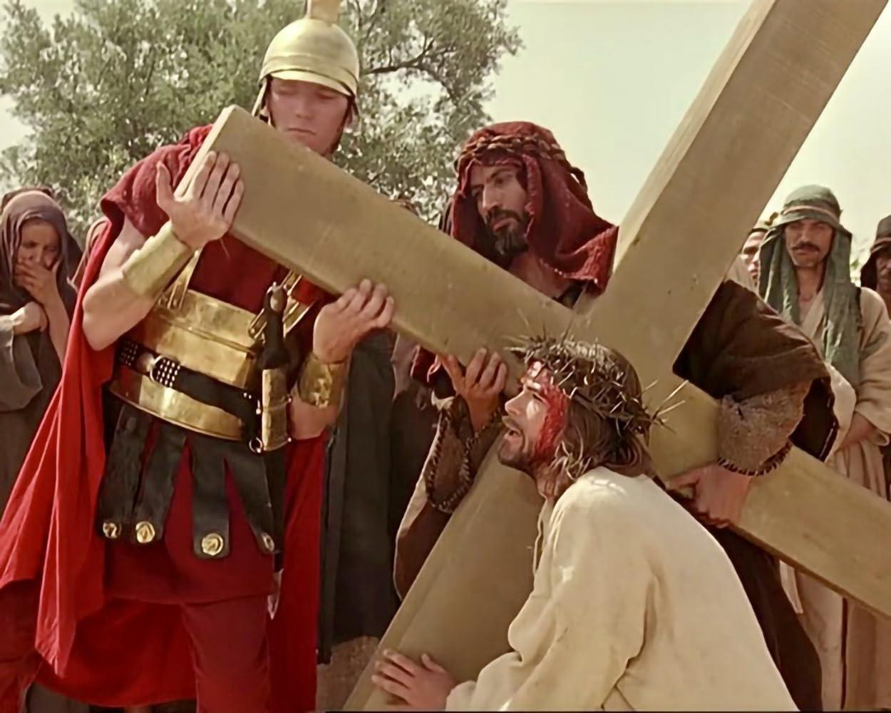 Mann trägt Kreuz, unterstützt von anderen. Römischer Soldat in Rüstung und Menschenmenge. Jesus mit Dornenkrone.