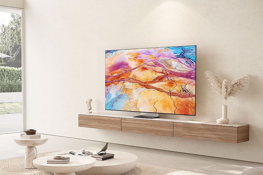 Salon avec une grande télévision affichant de l'art abstrait coloré. Une armoire basse en bois supporte la télévision. Deux tables basses blanches et une fenêtre.