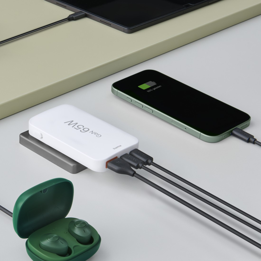 Eine weiße Powerbank mit Ladekabeln, die mit einem Telefon, Tablet und Ohrhörern verbunden sind. Das Telefon zeigt 80 % geladen an.