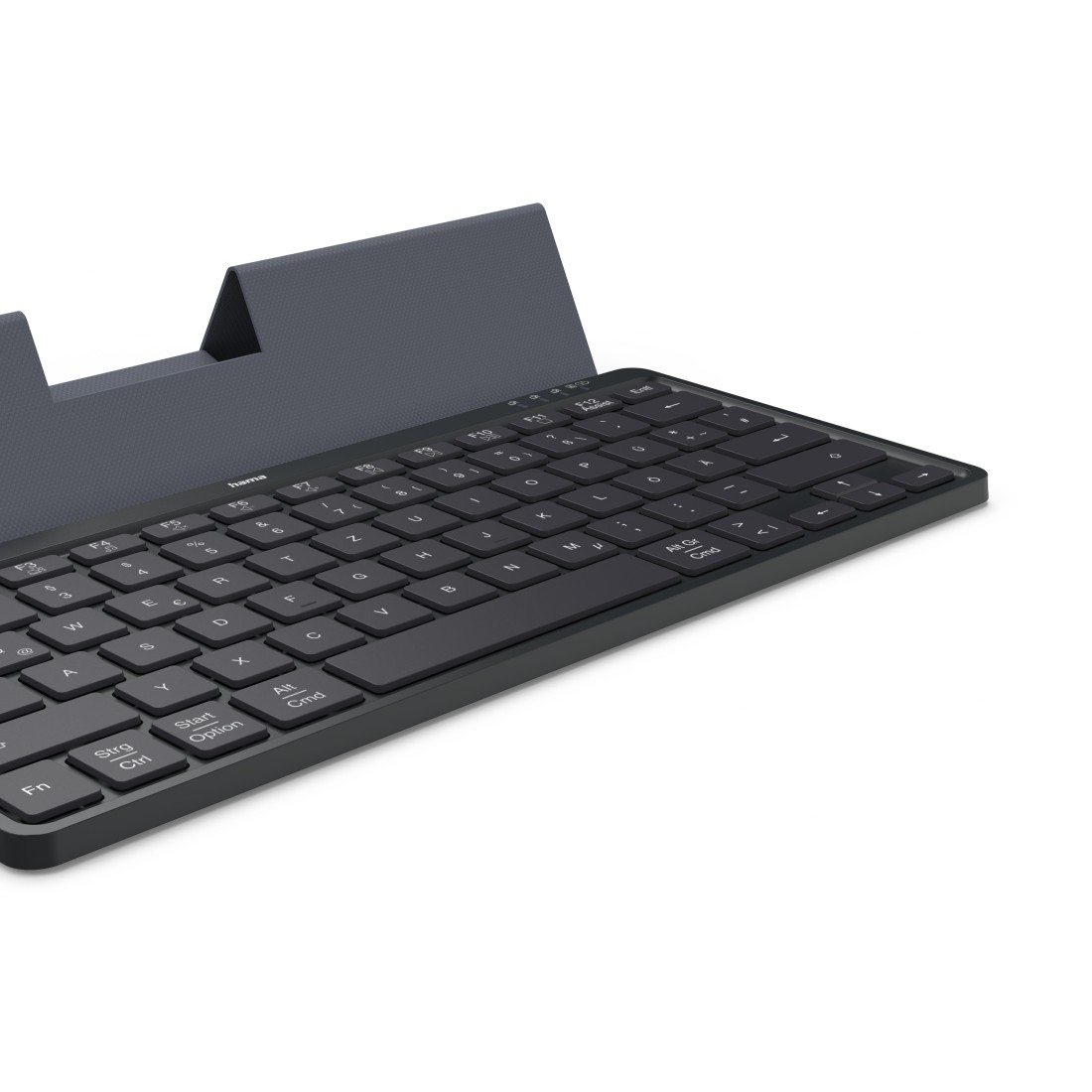 Schwarze Tastatur mit dunkelgrauer Abdeckung. Tasten sind sichtbar. Die Tastatur liegt auf einer weißen Oberfläche.