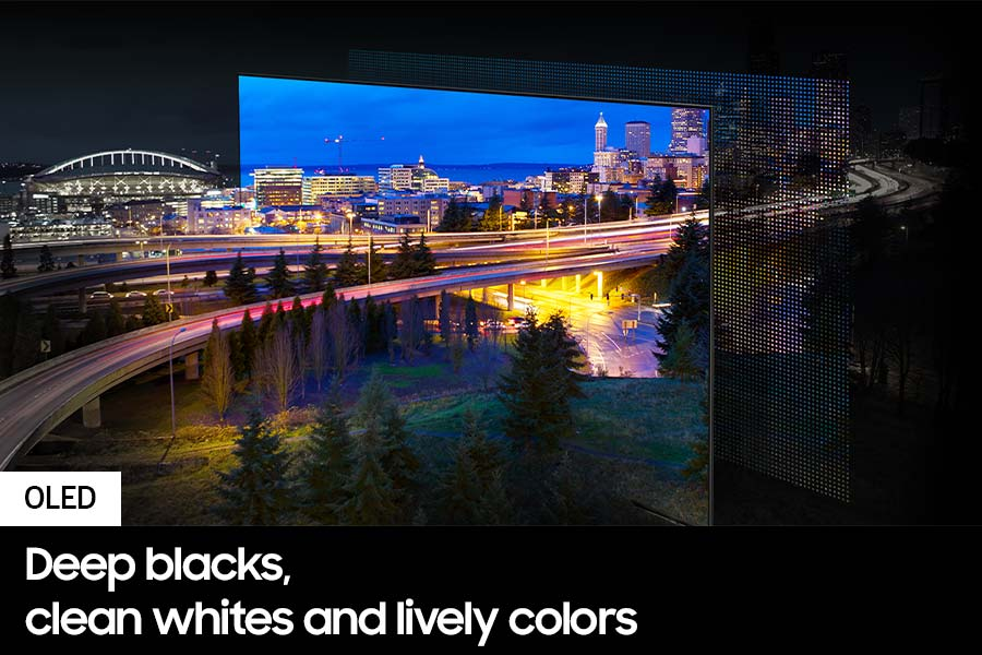 Un display OLED mostra lo skyline notturno di una città. Autostrade con luci di auto e alberi in primo piano.