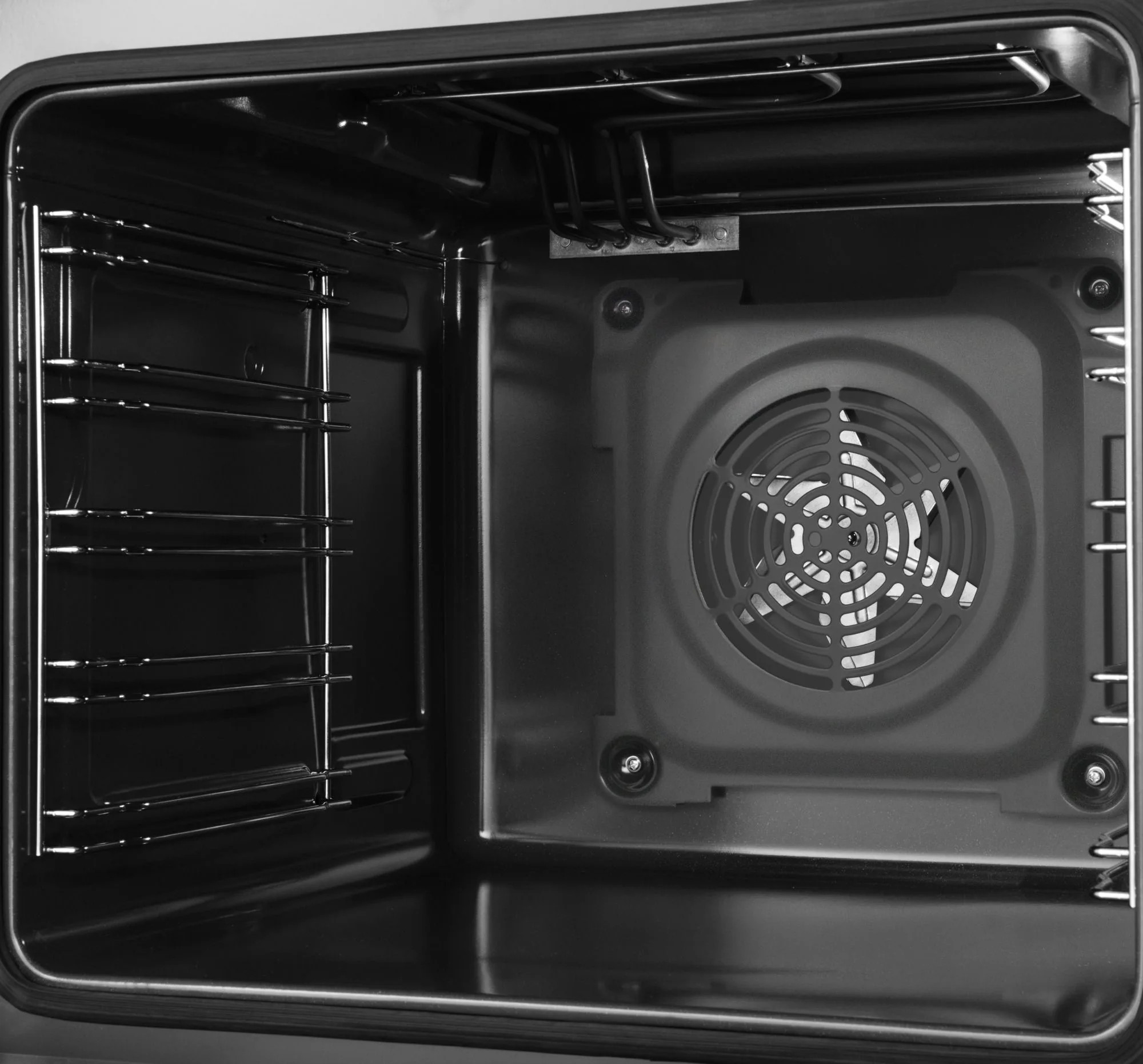 Wnętrze piekarnika. Wnętrze jest czarne, z rusztami po bokach. Wentylator znajduje się na tylnej ścianie.