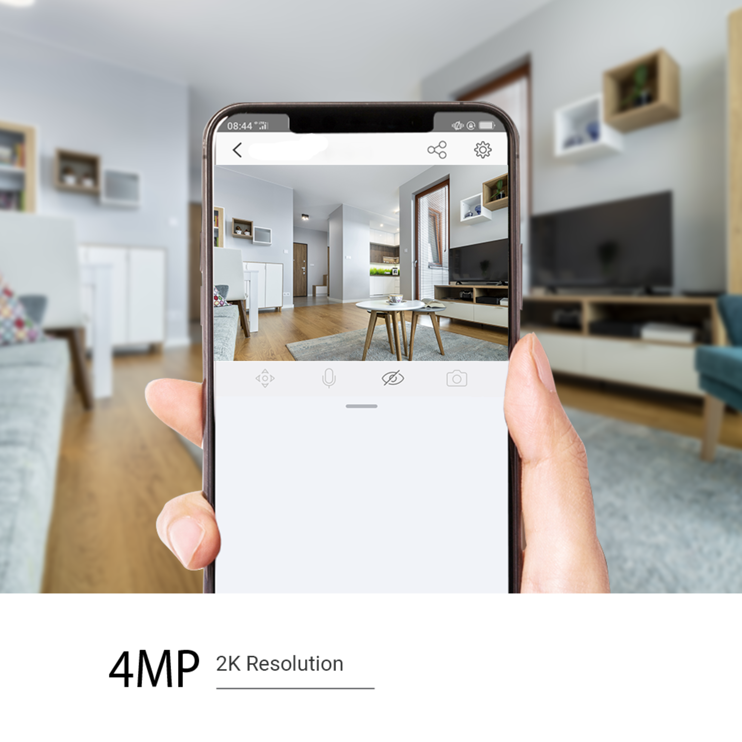 A hand holding a phone showing a living room view. The phone displays icons, and the background has a TV, couch, and other furniture.