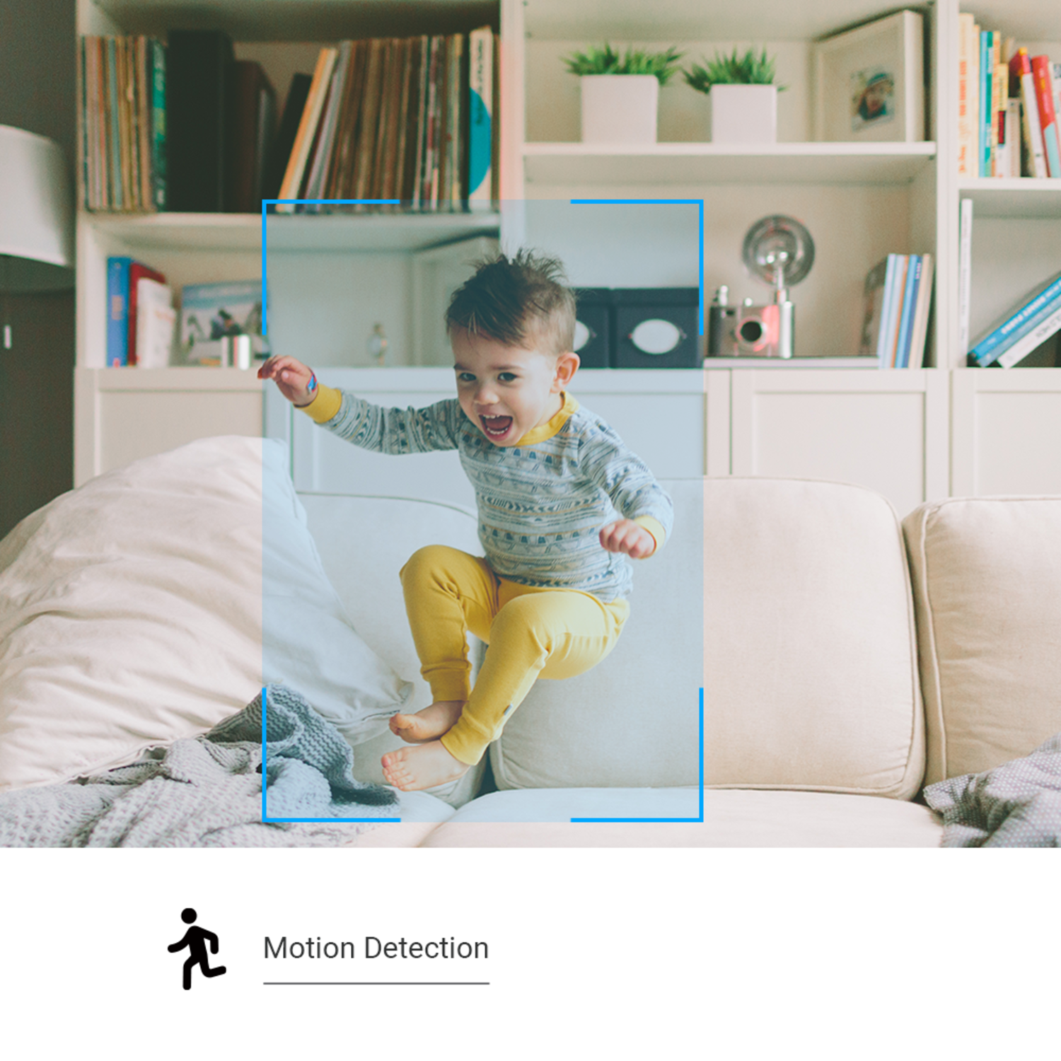 A child jumps excitedly on a sofa. The background shows a bookshelf with various items. The child wears yellow pants and a patterned top.