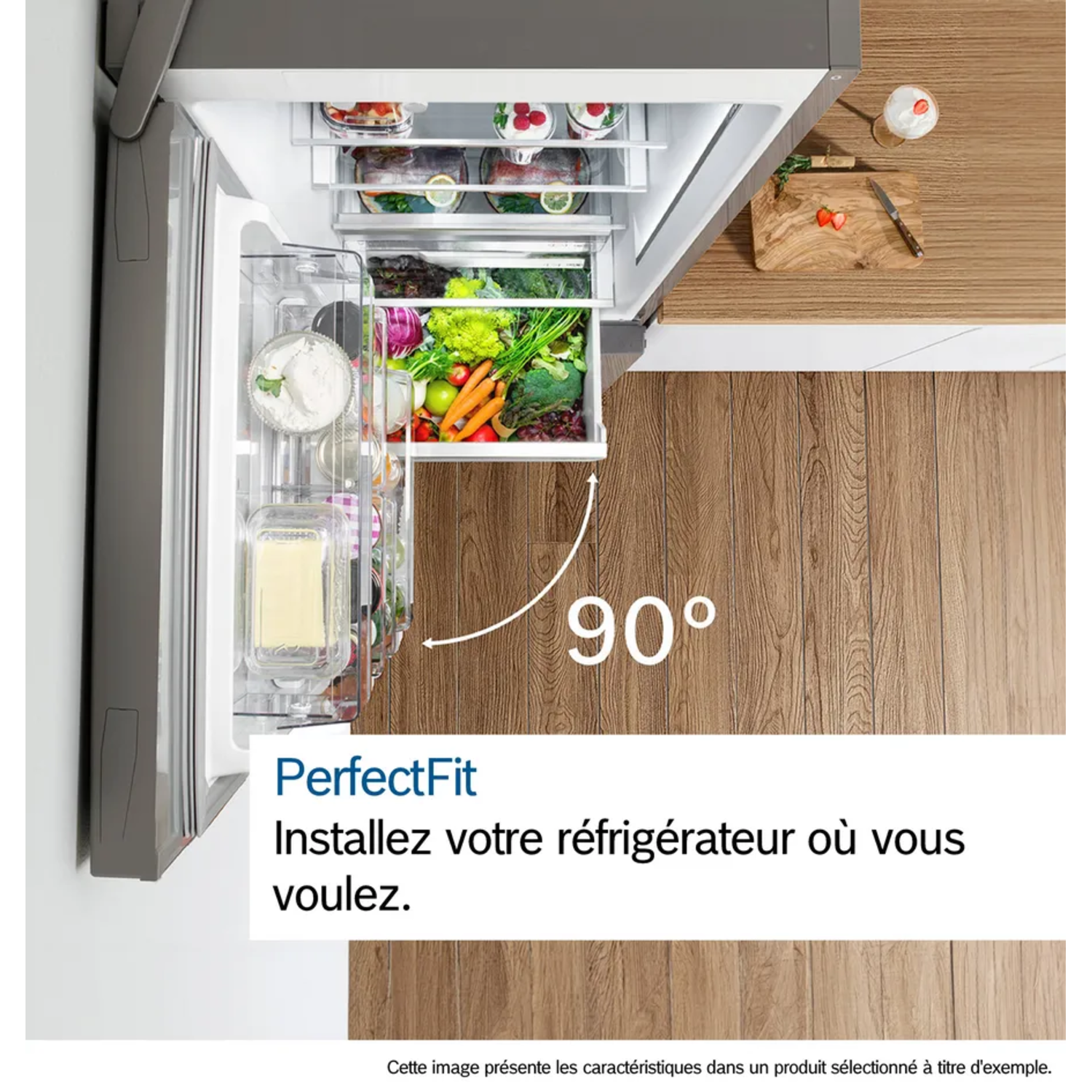 Réfrigérateur ouvert rempli de fruits et légumes. Une planche à découper avec des fraises et un verre de crème sont à côté.