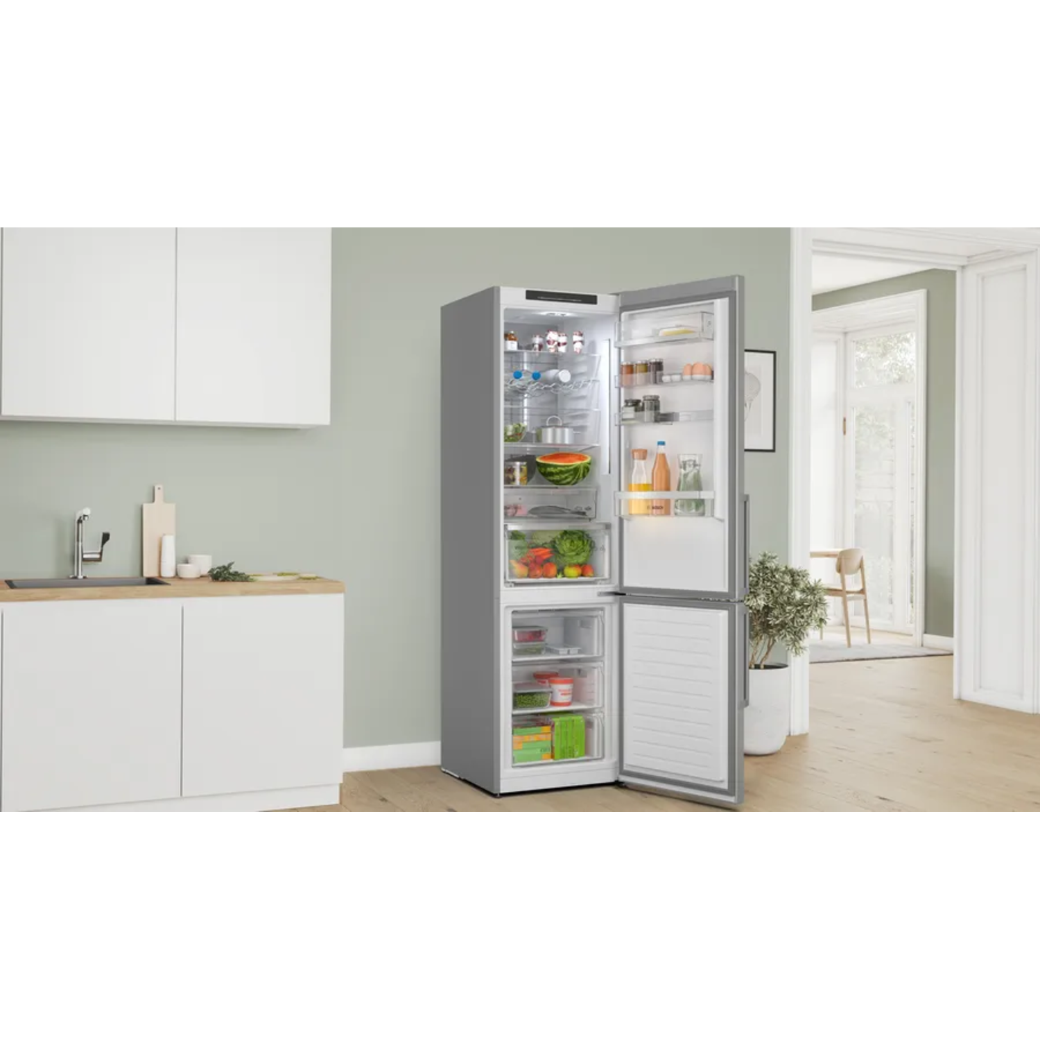 Un réfrigérateur avec une porte ouverte, montrant des produits frais, des boissons et d'autres aliments. Fond de cuisine avec des armoires blanches.