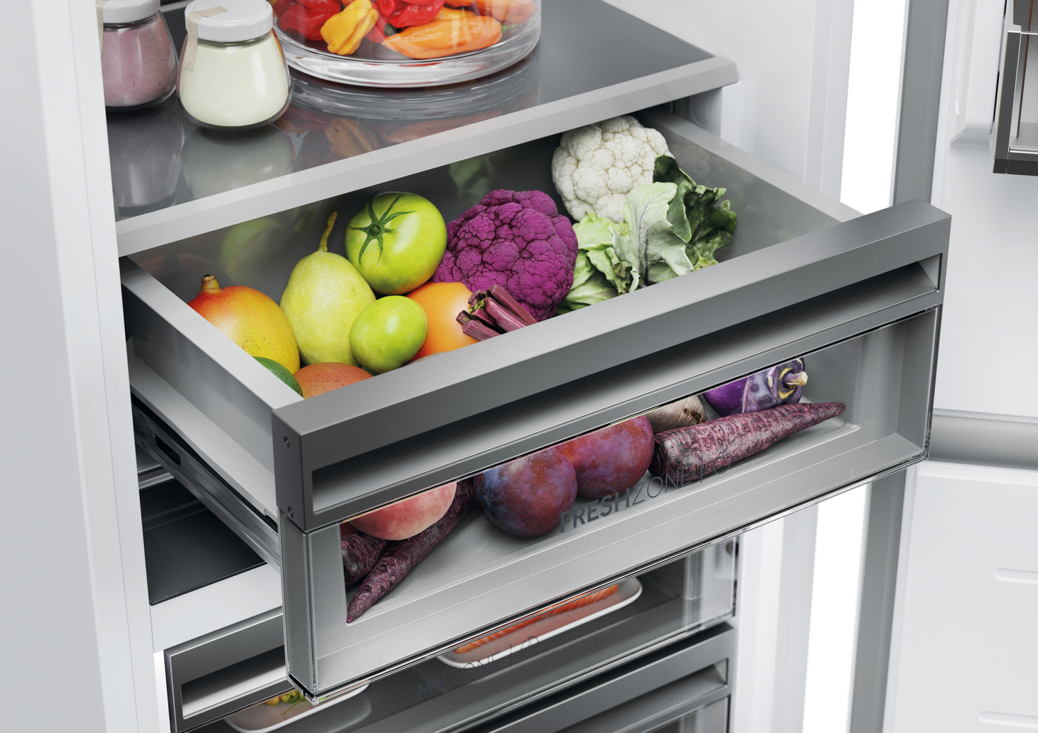 Un cajón de refrigerador lleno de productos frescos: frutas, verduras y una coliflor morada. También se ven otros cajones.