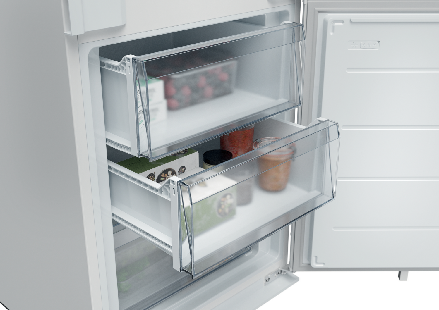 Vista de cerca dentro de un refrigerador, mostrando cajones transparentes llenos de alimentos envasados, frascos y recipientes.