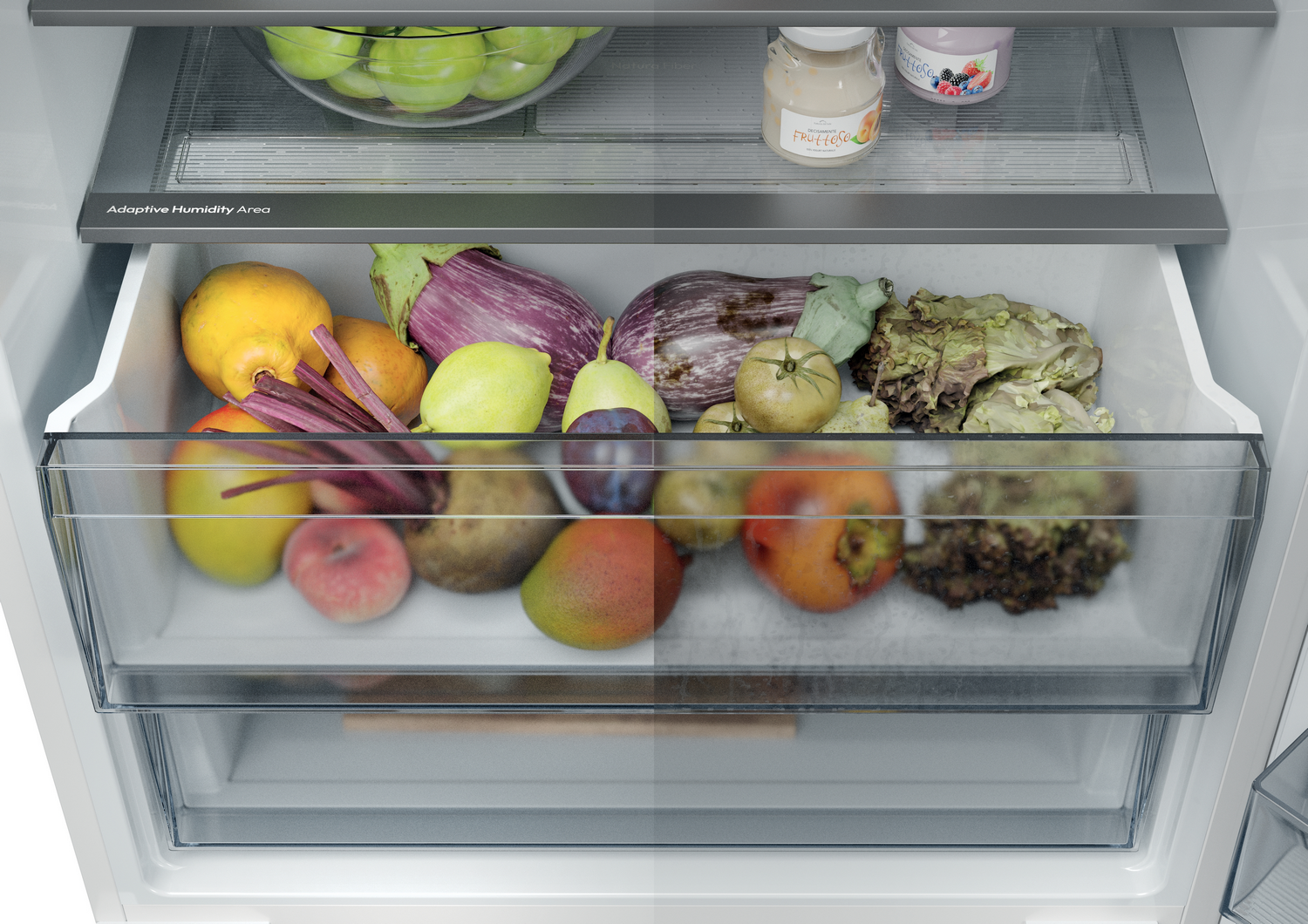 Interior de la nevera con frutas y verduras: manzanas, berenjenas, limones, tomates, mangos, lechuga y tarros de comida.