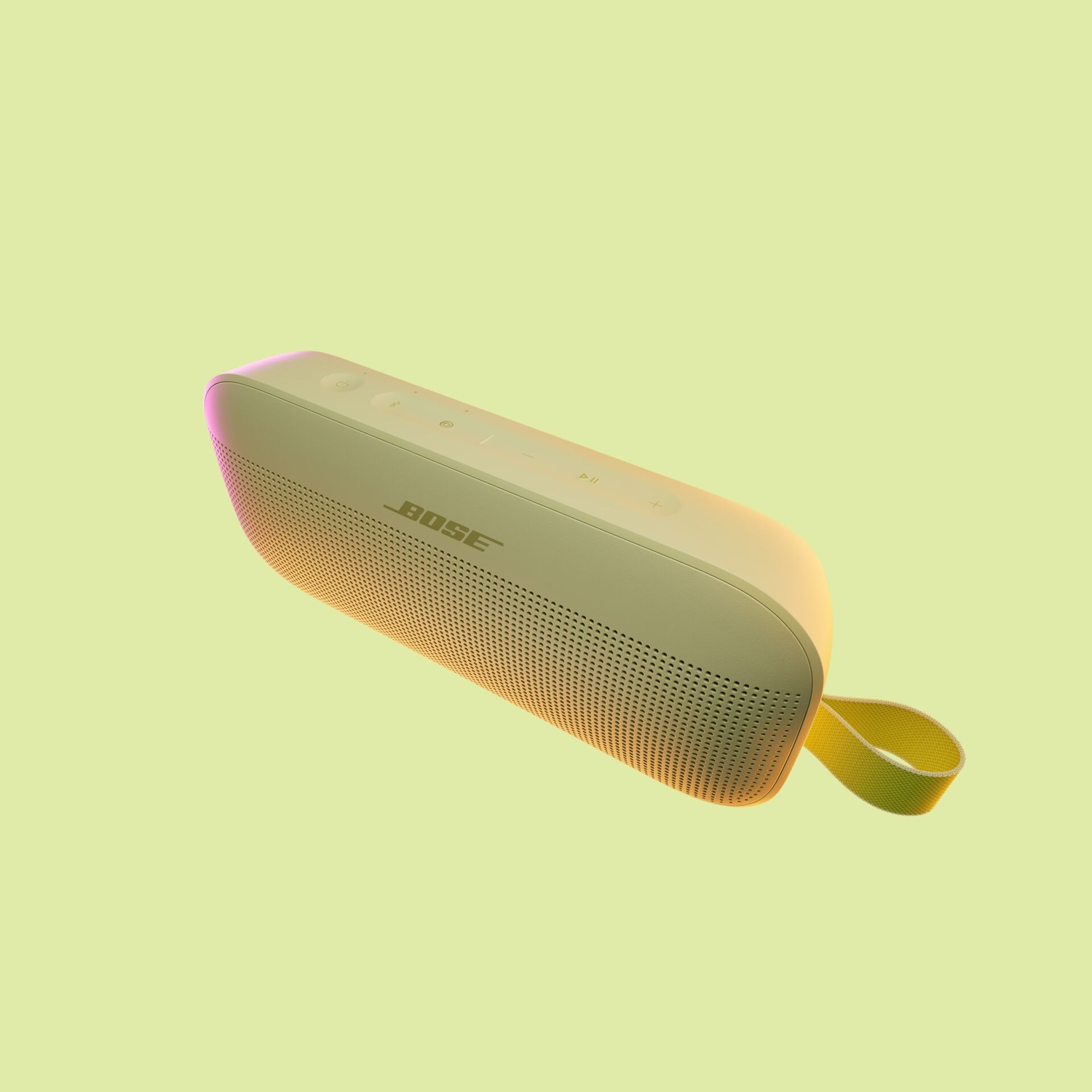 Un altoparlante Bose verde chiaro con una cinghia gialla fluttua su uno sfondo verde chiaro. L'altoparlante ha dei pulsanti.