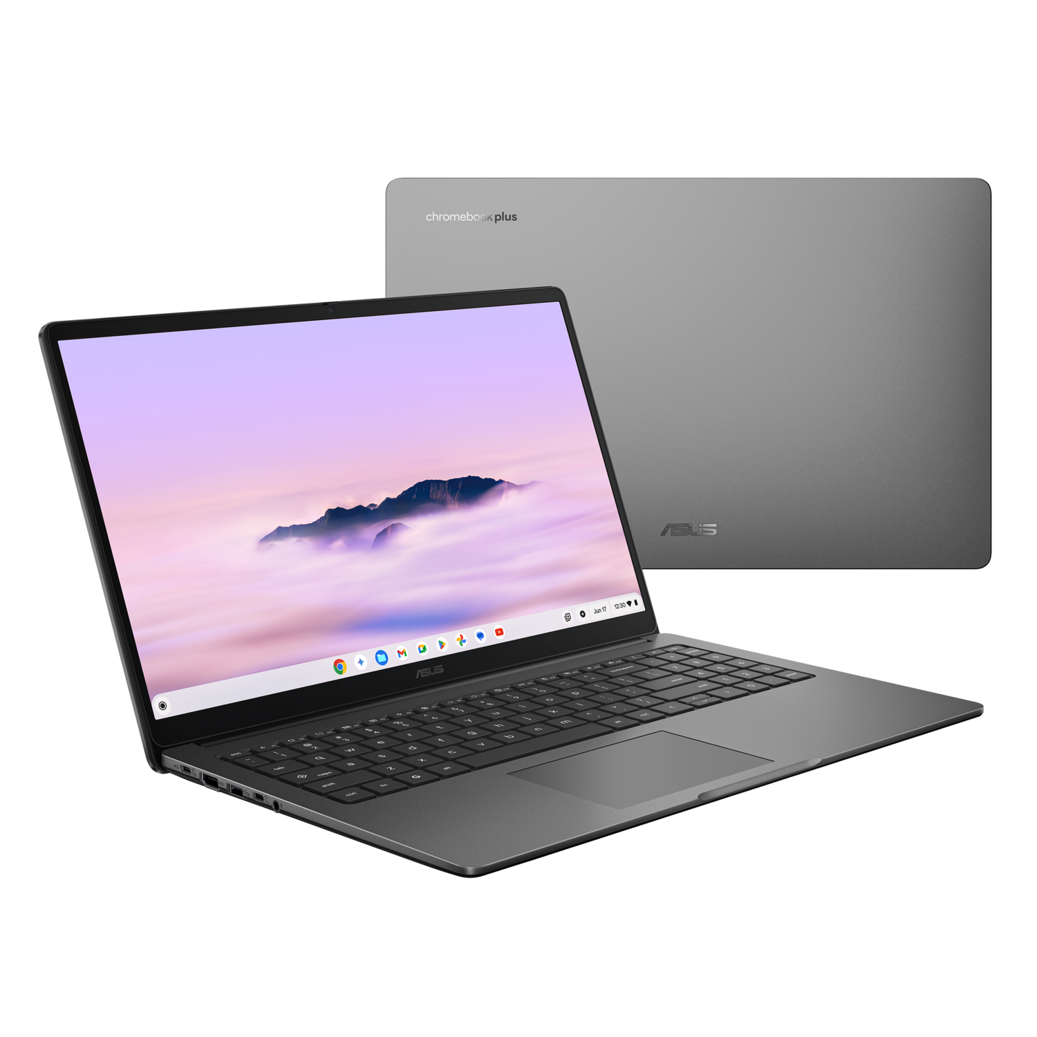 A gray ASUS Chromebook Plus laptop is displayed at an angle. The screen shows a mountain landscape. A second closed laptop is in the background.