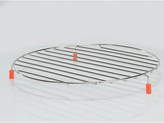 Okrągły ruszt chłodzący ze stali nierdzewnej z pomarańczowymi nóżkami, spoczywający na białej, odblaskowej powierzchni, na białym tle.