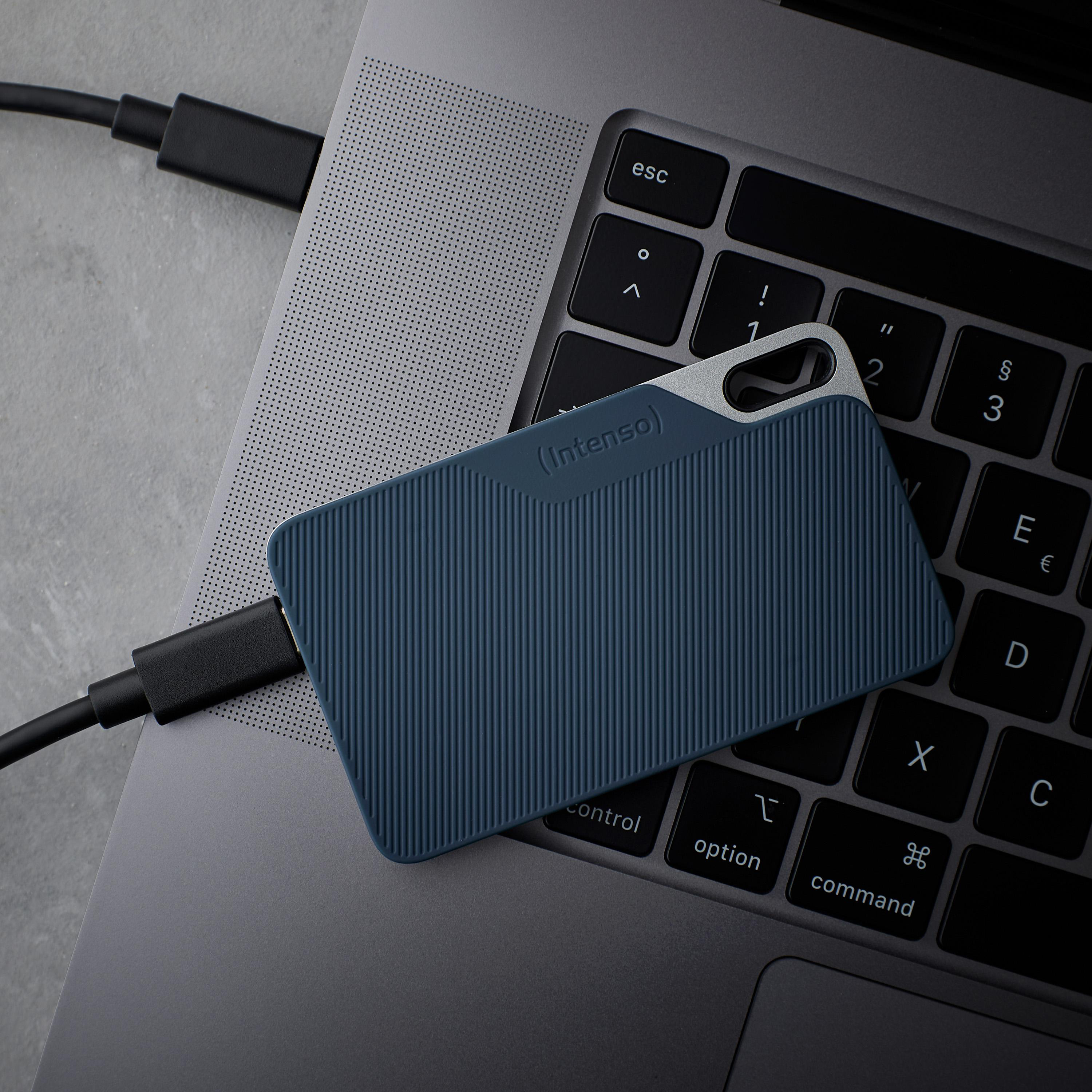 Un disco rigido esterno Intenso blu è appoggiato su una tastiera di un laptop, collegato tramite un cavo USB-C nero.