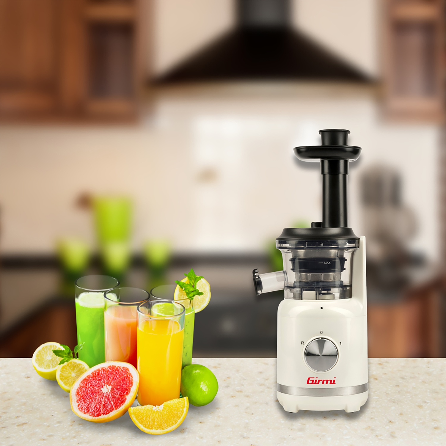 Un estrattore di succo bianco con dettagli neri, bicchieri di succo e frutta, come limone, pompelmo e lime, su un piano.