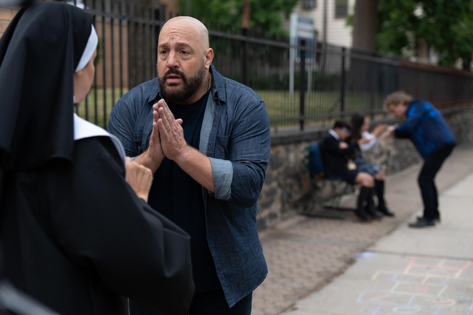 Ein Mann mit gefalteten Händen betet eine Nonne an. Andere Leute sind im Hintergrund.