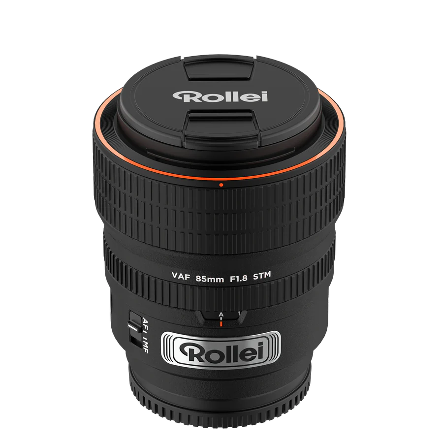 Ein schwarzes Kameraobjektiv mit Rollei-Logo auf Deckel und Gehäuse. Es hat einen orangefarbenen Ring und den Text "VAF 85mm F1.8 STM".