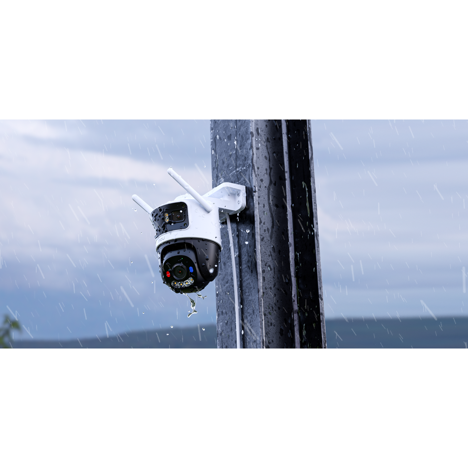 A security camera is mounted on a pole in the rain. It has white and black elements, with red and blue lights. Raindrops are visible.