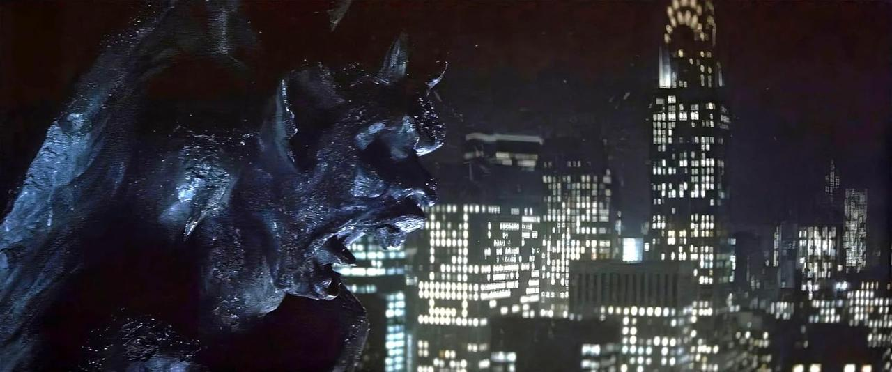 Eine Gargoyle-Statue blickt nachts auf die Skyline einer Stadt. Gebäude sind mit vielen Lichtern beleuchtet. Die Szene ist düster und stimmungsvoll.