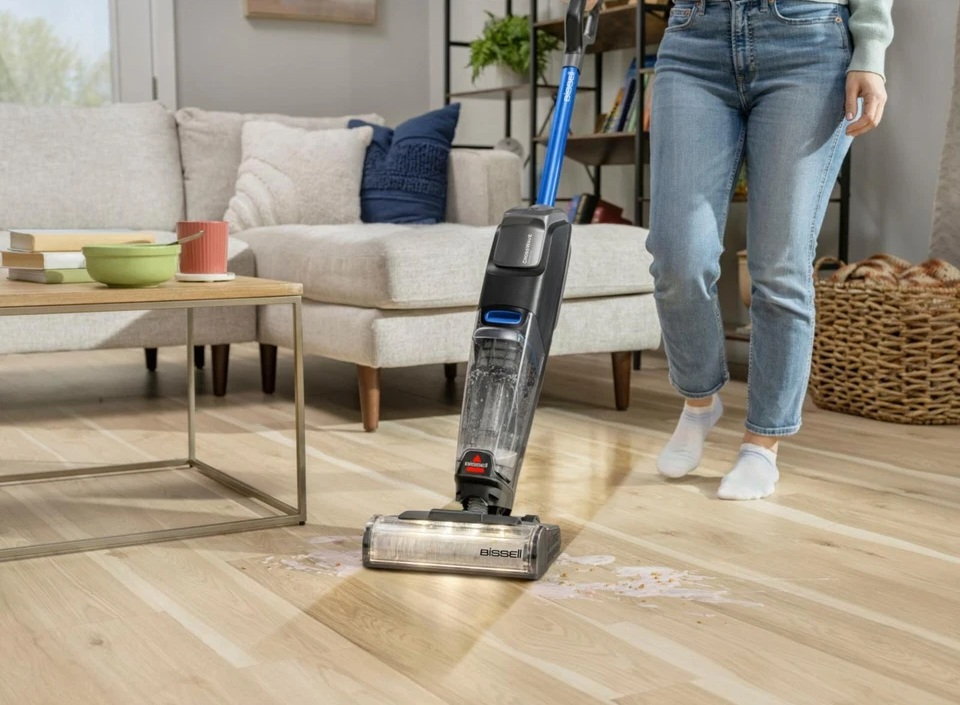 Kobieta używa Bissell CrossWave na drewnianej podłodze. W tle sofa, stolik kawowy i kosz.