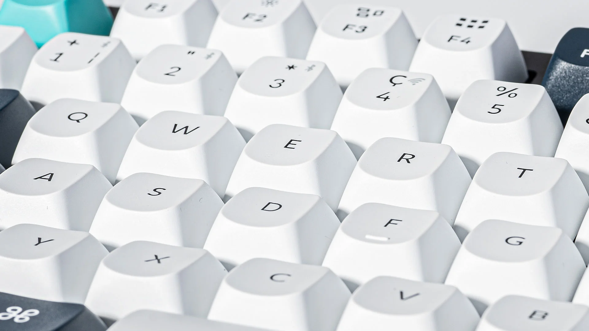 Nahaufnahme einer weißen mechanischen Tastatur. Die Tasten sind weiß mit schwarzen Buchstaben und Symbolen. Ein paar Tasten haben eine andere Farbe.