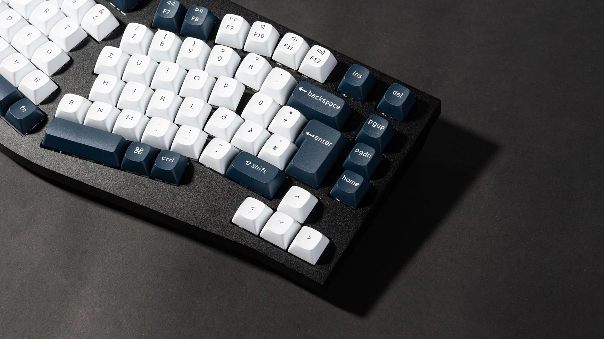 Eine mechanische Tastatur mit weißen und blauen Tasten. Der Hintergrund ist dunkelgrau. Tastenbeschriftungen sind sichtbar.