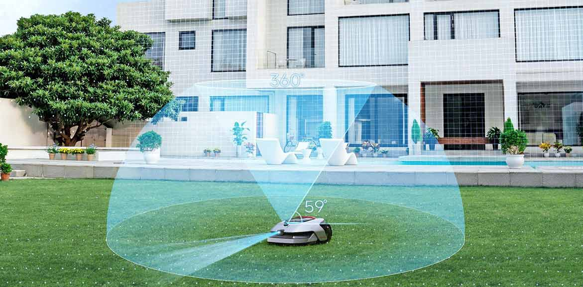 Robotfűnyíró zöld füvön. Modern ház a háttérben, nagy fa bal oldalon.