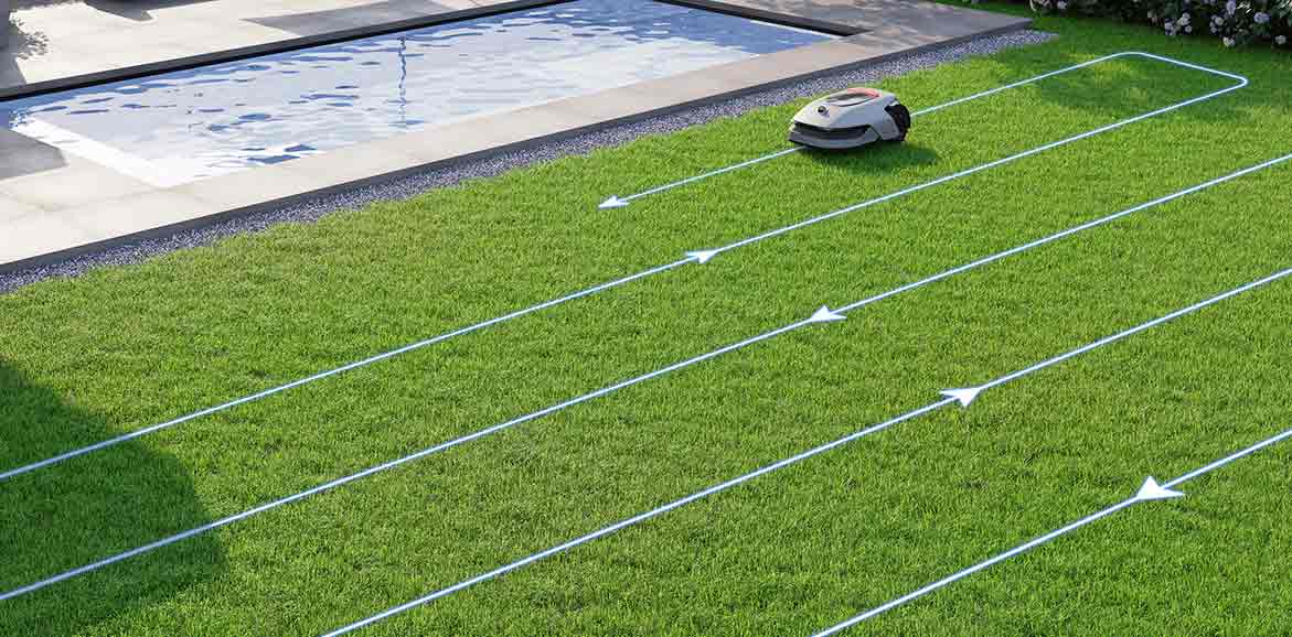 Robotfűnyíró zöld füvön. Fehér vonalak mutatják az útját. A háttérben egy medence látható.