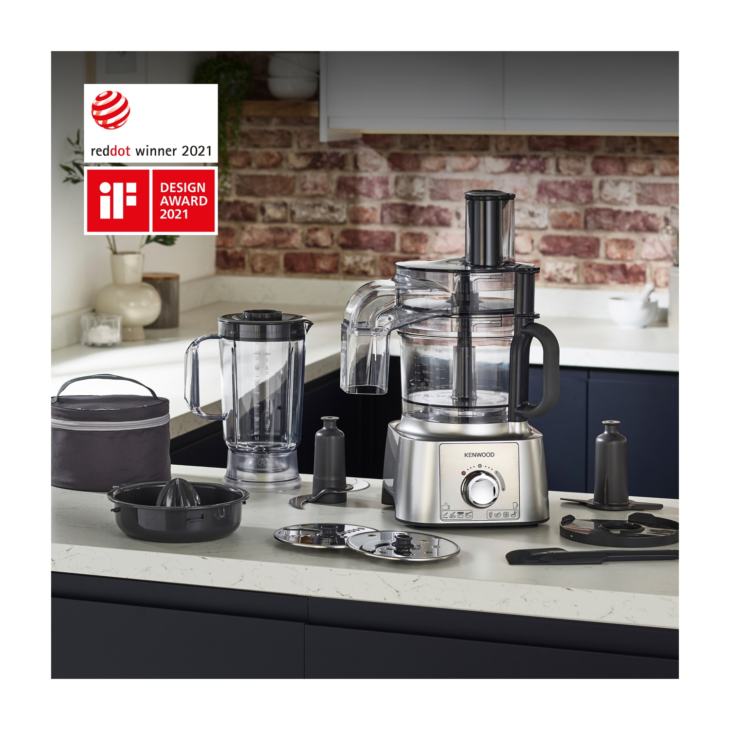 Robot da cucina Kenwood con frullatore, spremiagrumi e accessori su un piano di lavoro. Riconoscimenti visualizzati sullo sfondo. Ambiente cucina.