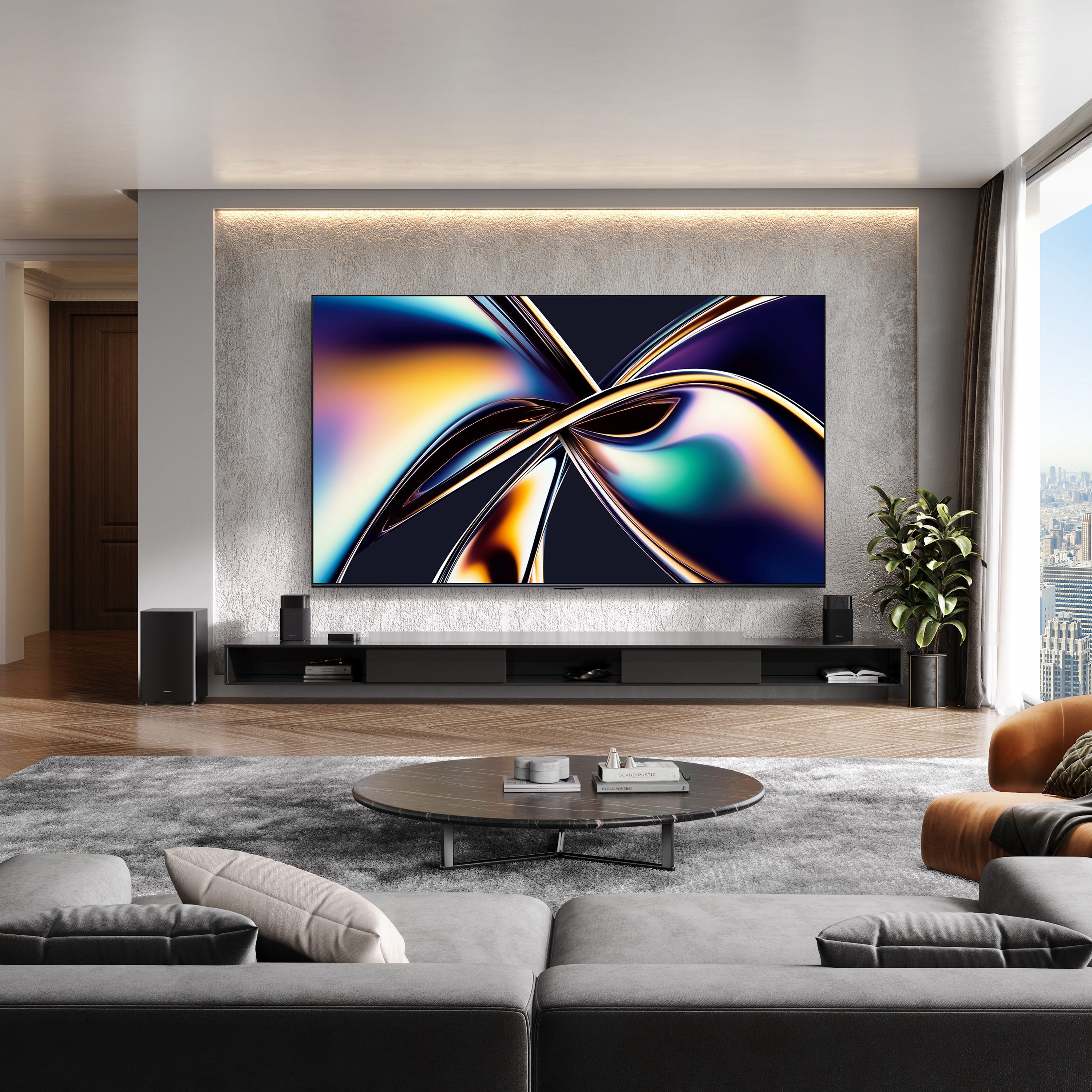 Nowoczesny salon z dużym telewizorem wyświetlającym kolorową sztukę. Szara sofa, okrągły stół i widok na miasto.