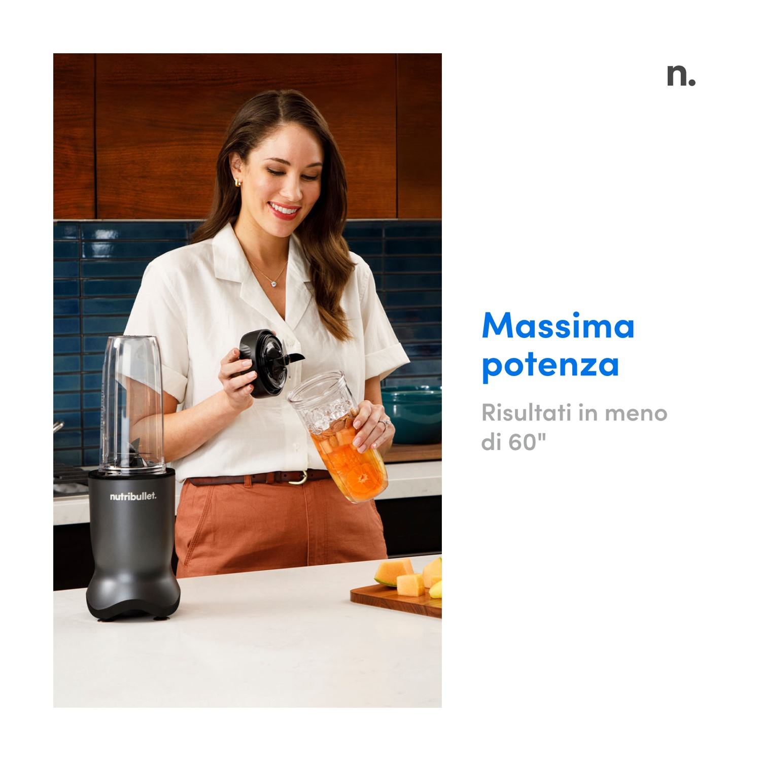 Donna in cucina tiene bicchiere frullatore, lo riempie. Frullatore sul bancone. Frutta su tagliere. Testo a destra.