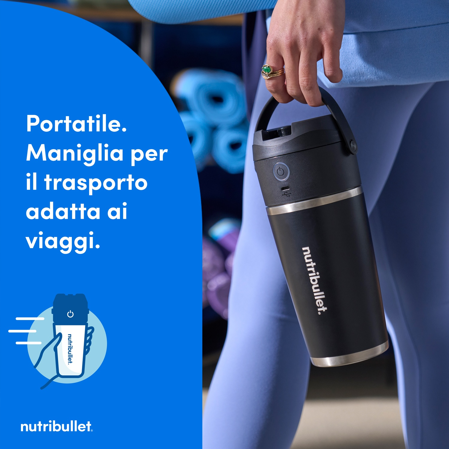 Una persona tiene in mano una borraccia da viaggio Nutribullet nera. La borraccia è nera con bordo argentato. La persona indossa abiti blu.