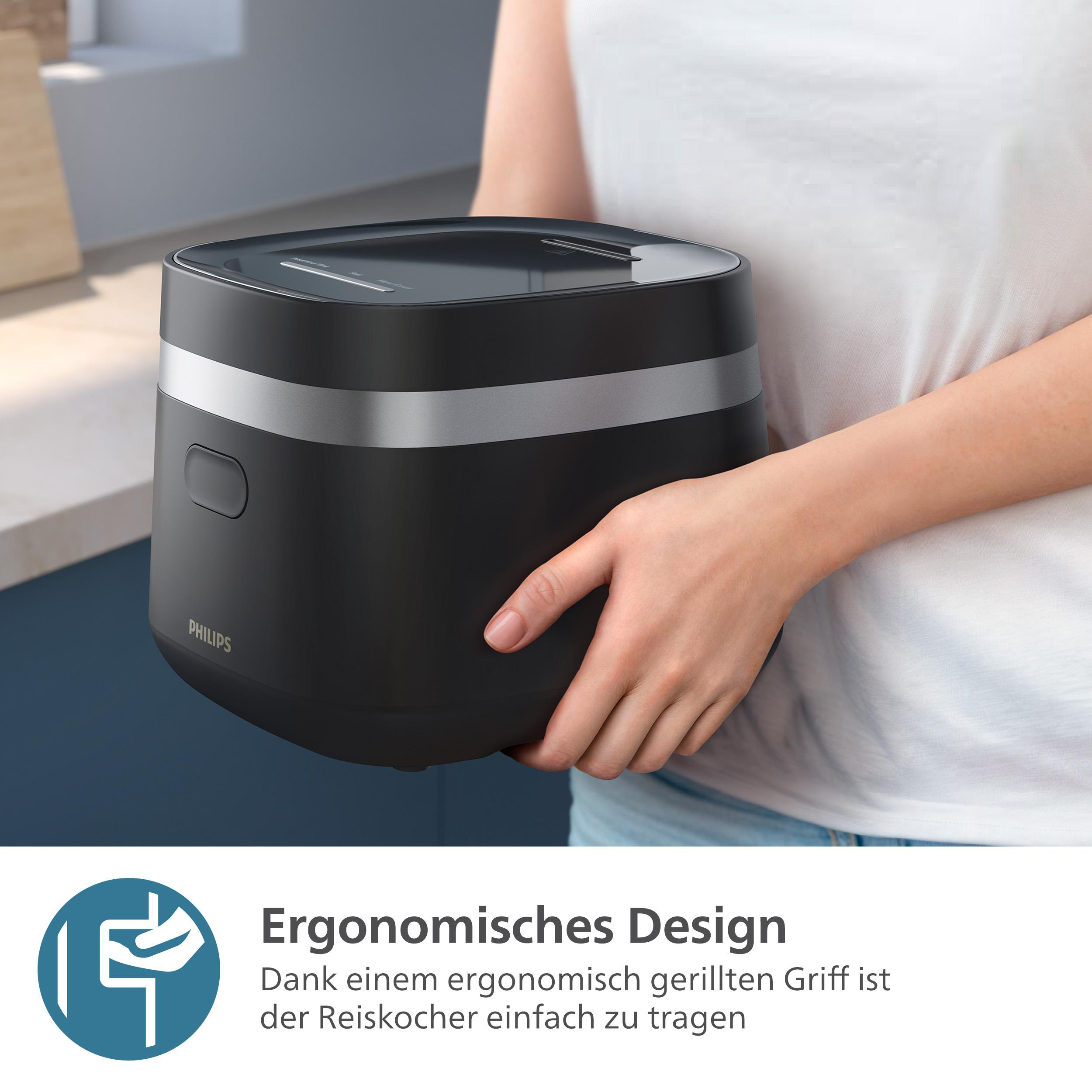 Eine Person hält einen schwarzen Reiskocher. Der Kocher hat ein silbernes Band und das Philips-Logo. Der Hintergrund ist unscharf.