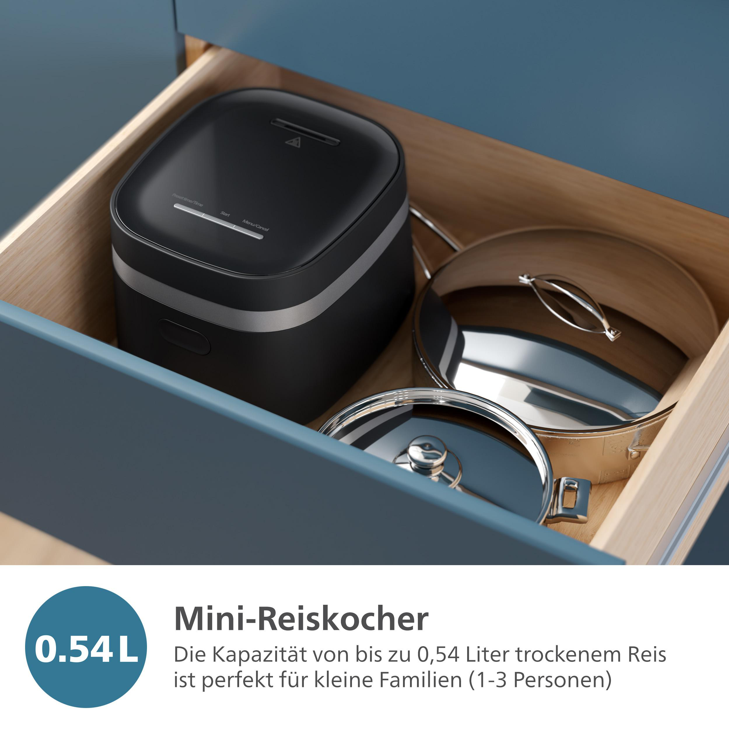 Ein schwarzer Reiskocher und zwei silberne Töpfe in einer offenen Schublade in einem blauen Schrank.