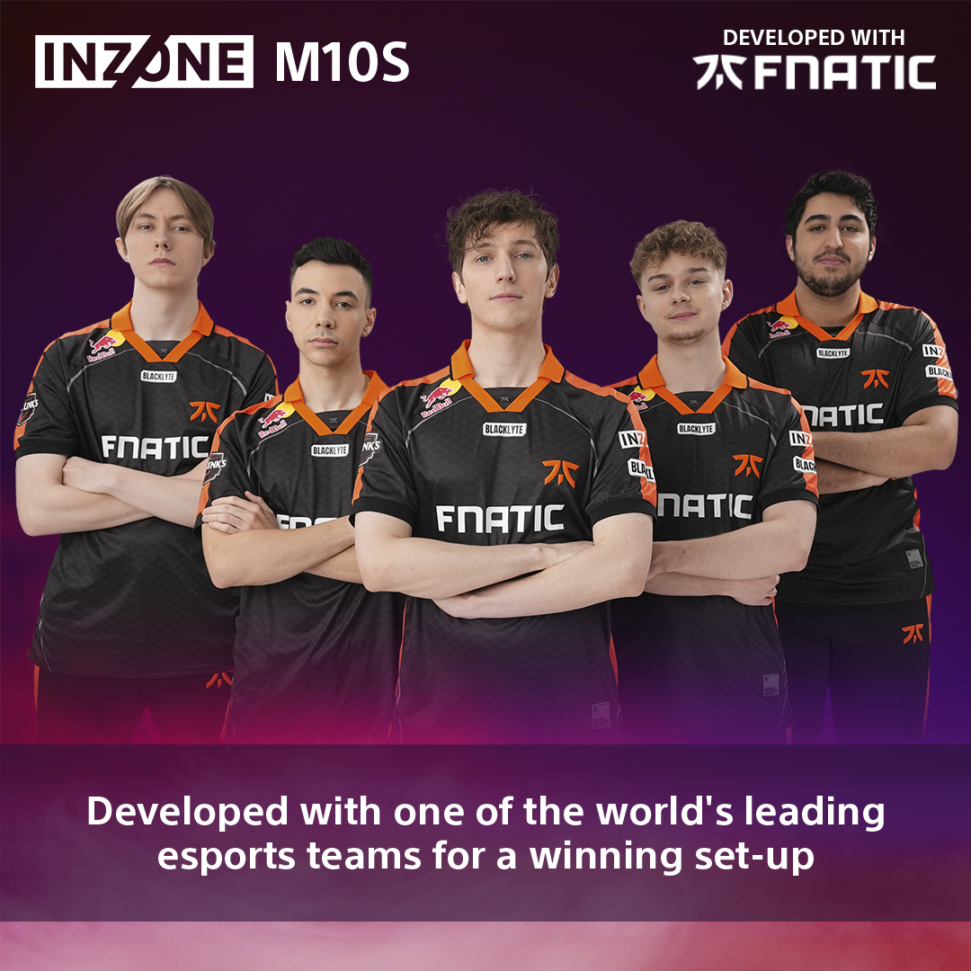 Cinq personnes en maillots Fnatic se tiennent debout, les bras croisés. Le fond est violet. Le texte dit 'Développé avec Fnatic'.