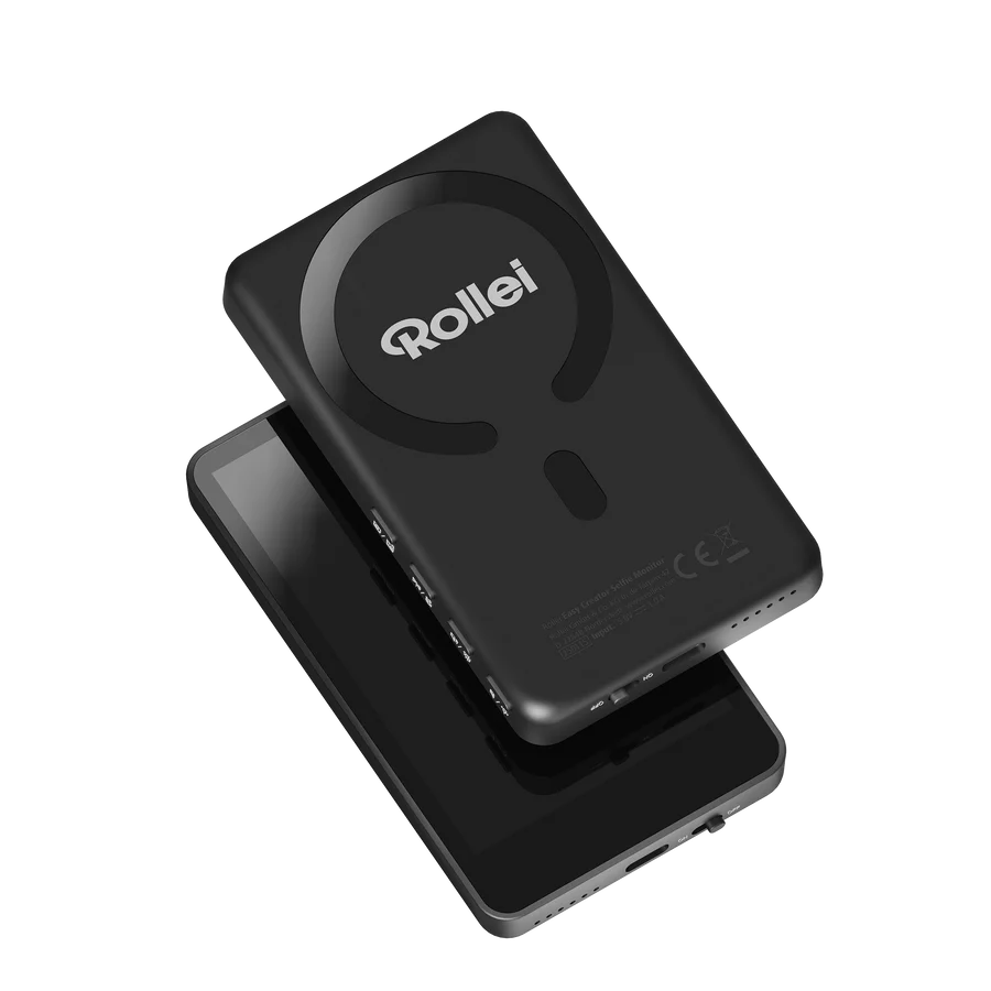 Ein schwarzes Rollei-Gerät liegt auf einem schwarzen Telefon. Rollei hat ein kreisförmiges Design, mit sichtbarem Logo. Der Hintergrund ist schwarz.