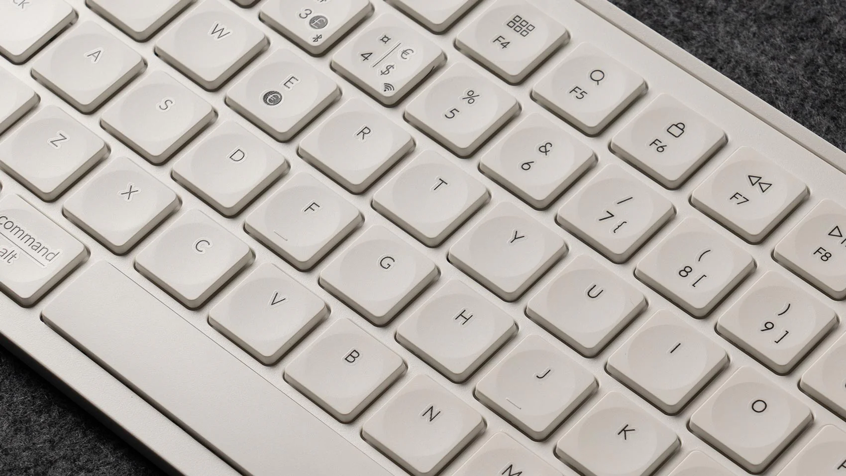 Nahaufnahme einer weißen Tastatur. Tasten mit Buchstaben und Symbolen sichtbar. Hintergrund ist eine graue Oberfläche.