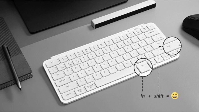 Weiße Tastatur auf grauem Schreibtisch. Fn- und Shift-Tasten hervorgehoben, mit Gleichung: Fn + Shift = lächelndes Gesicht.