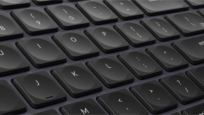 Nahaufnahme einer dunklen Tastatur. Die Tasten sind schwarz mit weißen Buchstaben und Symbolen. Buchstaben wie I, O, P, J, K und L sind sichtbar.