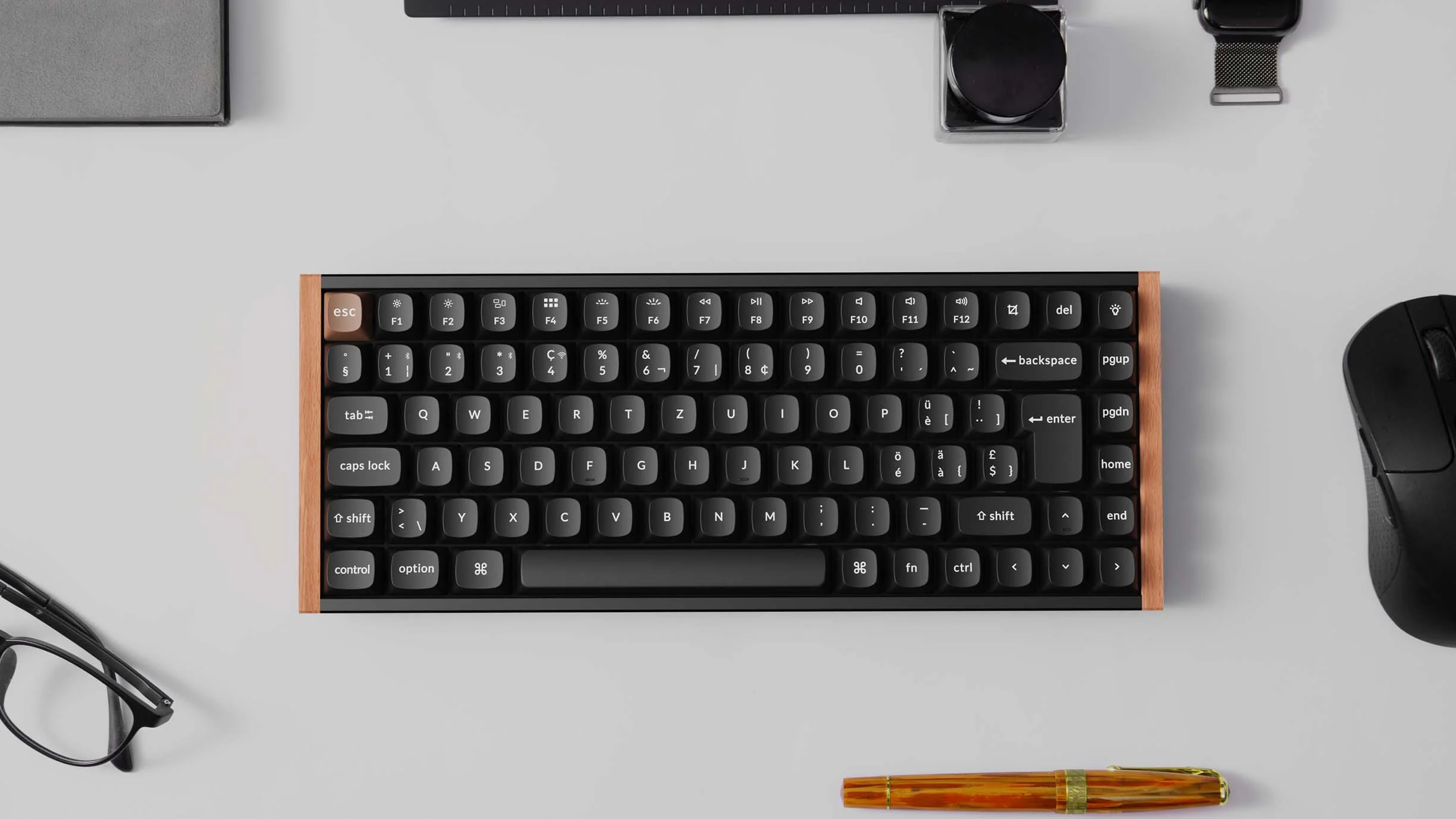 Schwarze Tastatur mit Holzrahmen auf weißer Oberfläche. Maus und Stift sind ebenfalls vorhanden. Objekte sind ordentlich angeordnet.