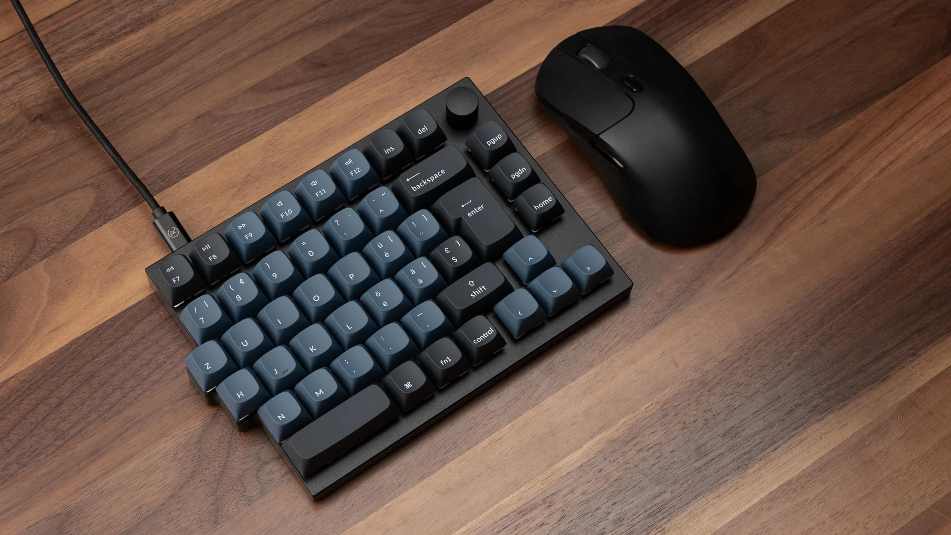 Eine schwarze Tastatur mit blauen Tasten und eine schwarze Maus auf einem Holztisch. Die Tastatur ist mit einem Kabel verbunden.