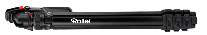 Ein schwarzes Rollei-Stativ, zusammengeklappt. Es hat rote Akzente und einen gummierten Griff. Der Markenname ist weiß.