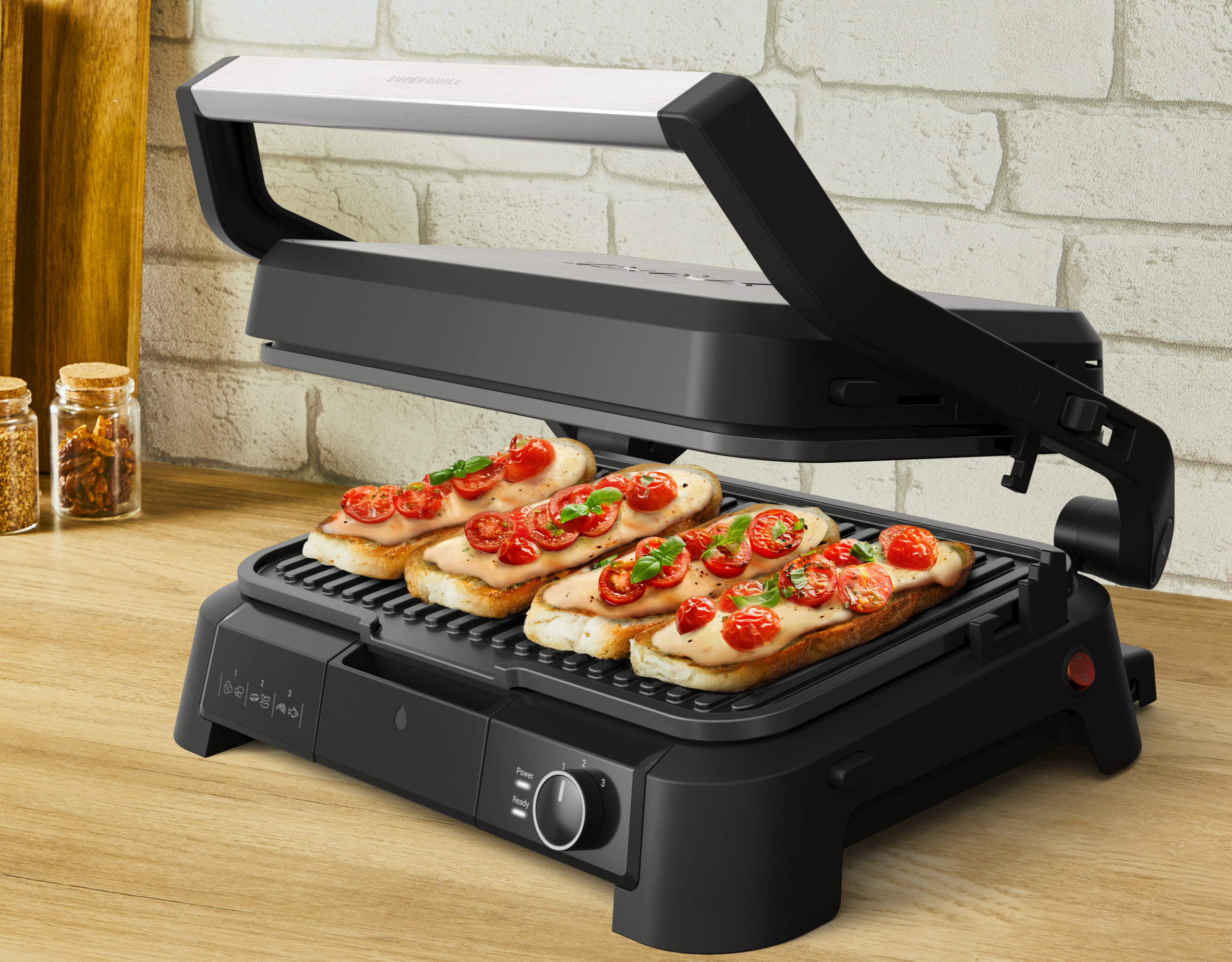 Grill do kanapek z tostowanym chlebem, pomidorami i bazylią. Grill jest otwarty, pokazując jedzenie i drewnianą powierzchnię.