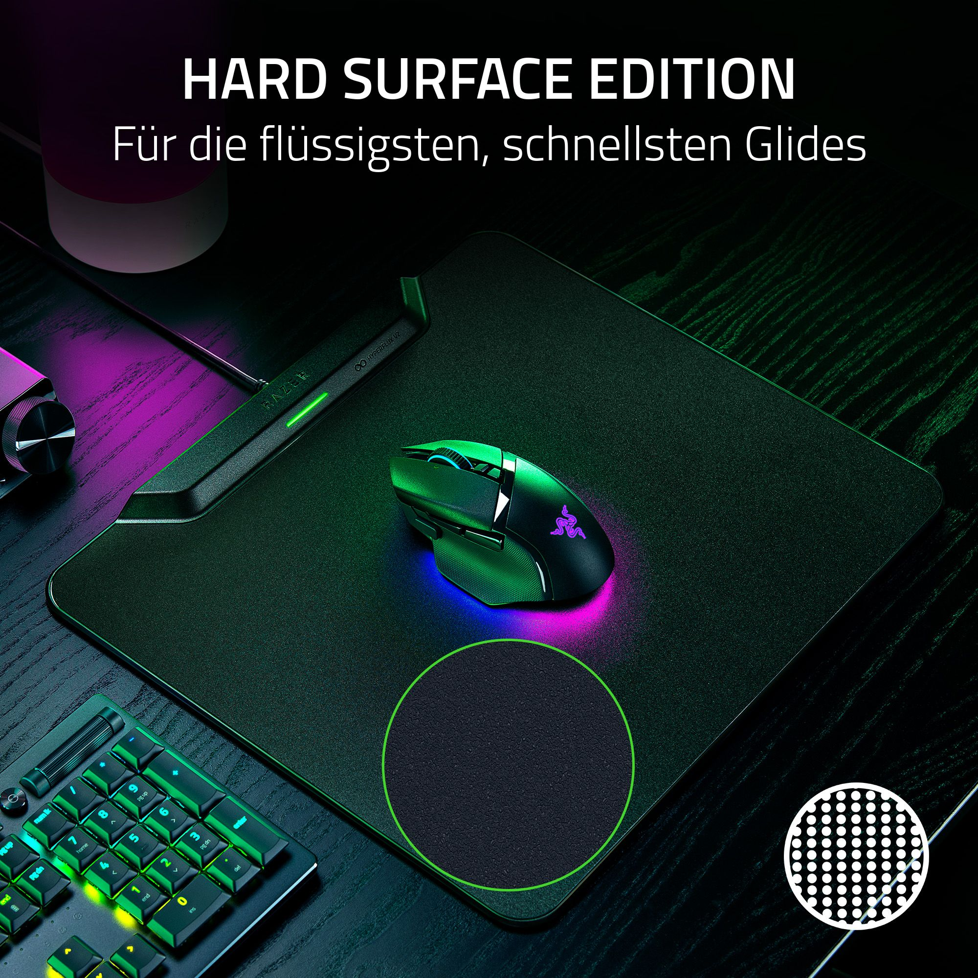 Eine Gaming-Maus auf einem schwarzen Mauspad. Pad und Maus sind mit grünen, pinken und blauen Lichtern beleuchtet. Eine Tastatur ist sichtbar.