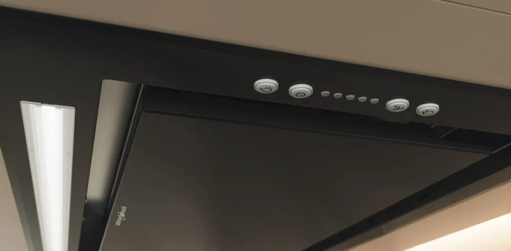 Czarny okap kuchenny z białymi przyciskami i oprawą oświetleniową. Przyciski mają symbole. Widoczne logo Whirlpool.