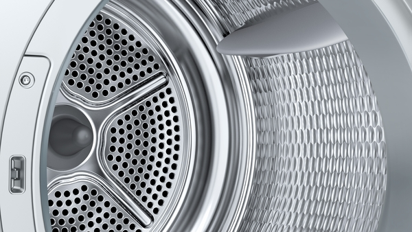 Nahaufnahme des Trommelinneren einer Waschmaschine. Perforierte Metalltrommel mit silbernem Finish. Das Innere ist sauber und hat ein Wabenmuster.