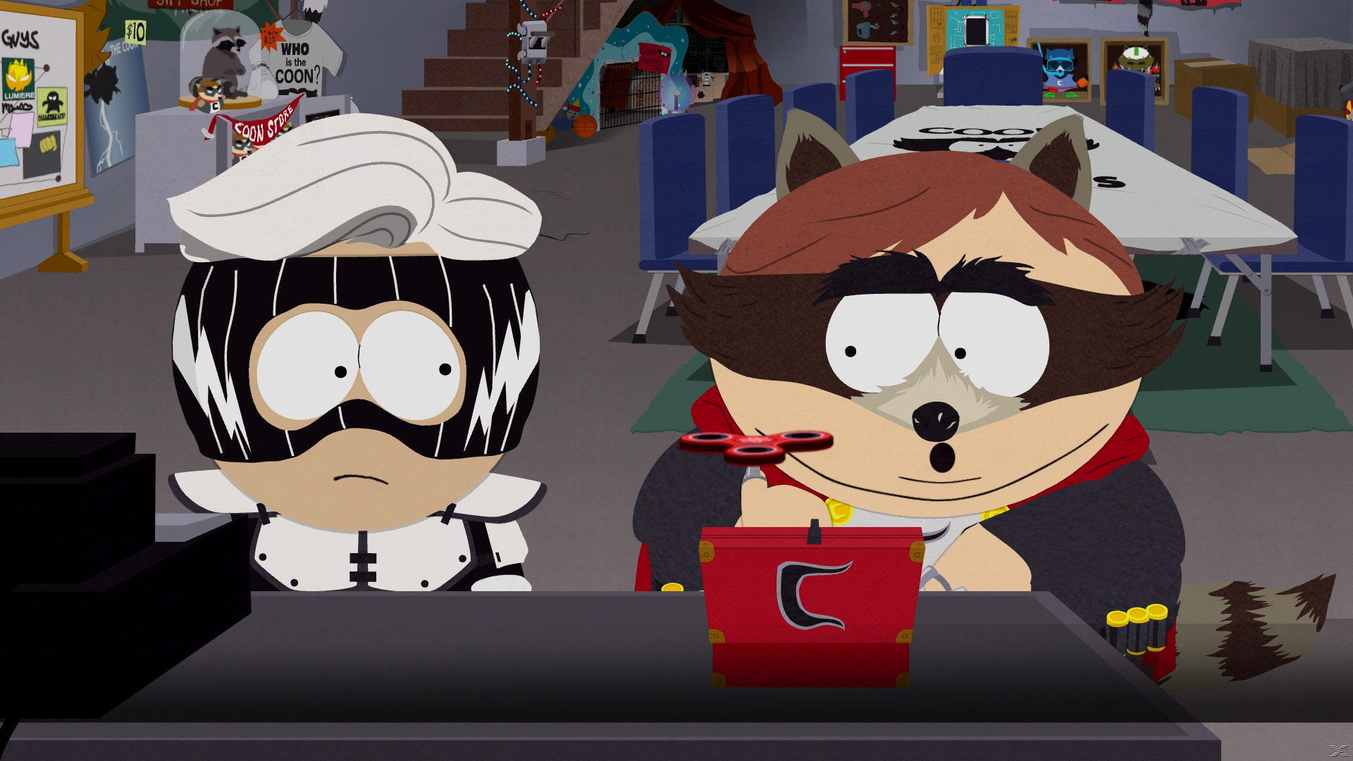 Zwei South Park-Charaktere: einer in Schwarzweiß, der andere in einem Waschbärenkostüm, mit einer roten Box und einem Fidget Spinner.