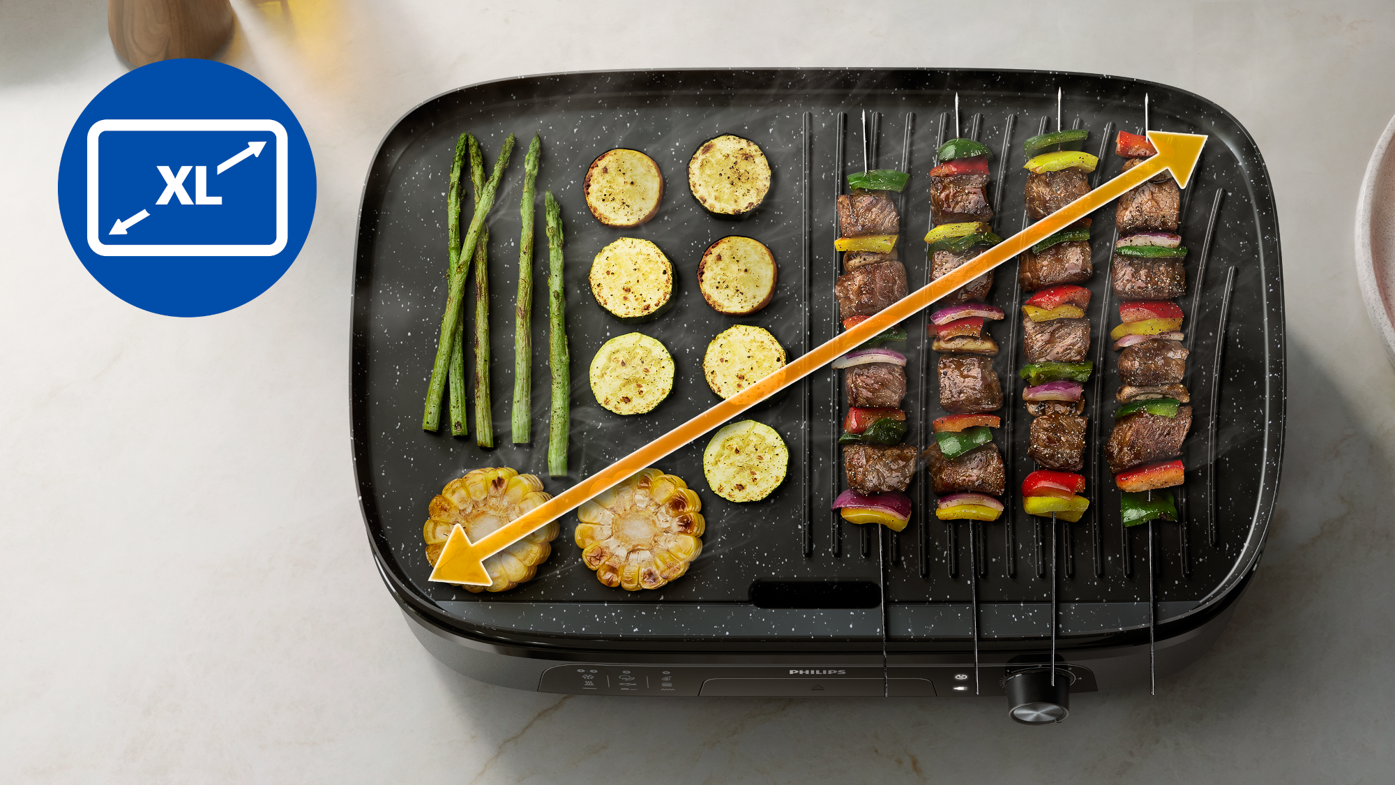 Grill zöldség- és hússzárnyasokkal. Bal oldalon spárga, cukkini és kukorica. Egy nyíl az XL méretet jelzi.