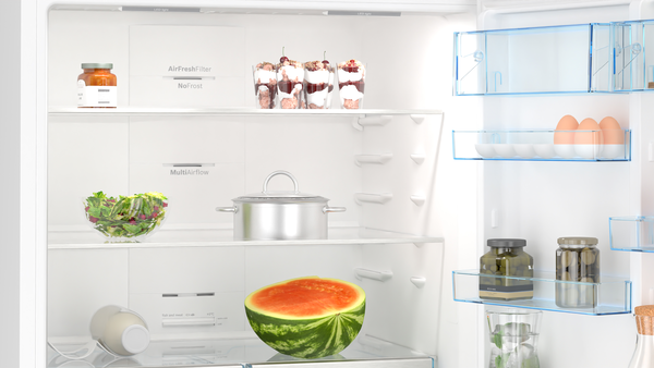 Yiyeceklerle dolu açık bir buzdolabı: kavanozlar, salata, karpuz, yoğurt, yumurta ve tatlılar.