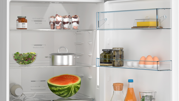 Buzdolabının içinde çeşitli yiyecekler var: kavanozlar, tatlılar, salata, bir tencere, karpuz, yumurta, meyve suyu şişeleri ve tereyağı.