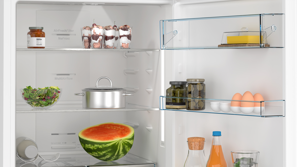 Buzdolabının içinde: salata, karpuz, kavanozlar, yumurtalar, tatlılar ve bir tencere. Raflarda yiyecekler görünüyor.